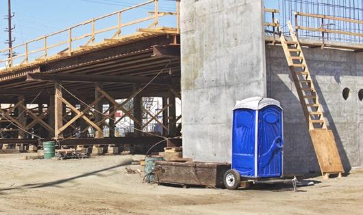 blue porta potties arranged in a neat line on a work site